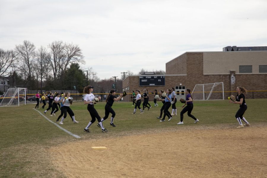 The softball team warms up during practice. The team looks to combat inexperience with team unity.
