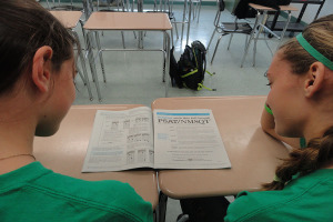 From left to right, sophmore Amy Santo and Carly Boyle take a peek at a PSAT booklet. SAT season can be a stressful time for students.