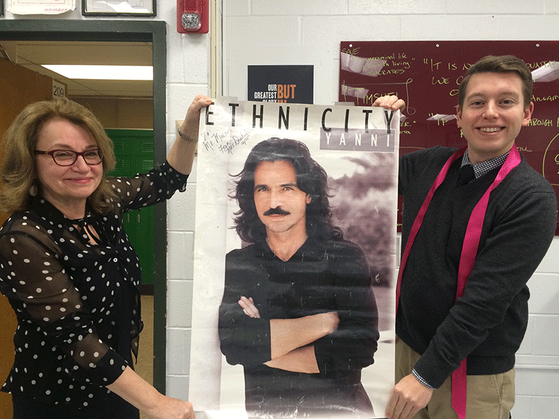 Mrs. Catherine Drakakis and Mr. Matt Morone unfurl the Yanni poster, which has hung on her wall for over 20 years.