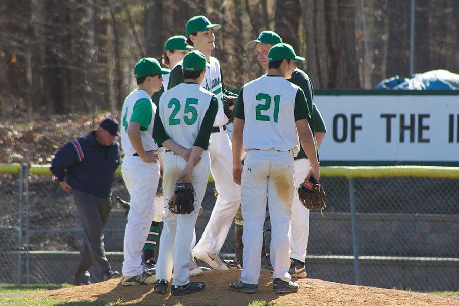 Baseball team gathers on the mound as Coach Will Lynch talks to the team