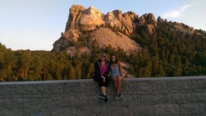 Mathias (left) and Jerome sitting on a wall in front of Mount Rushmore. 