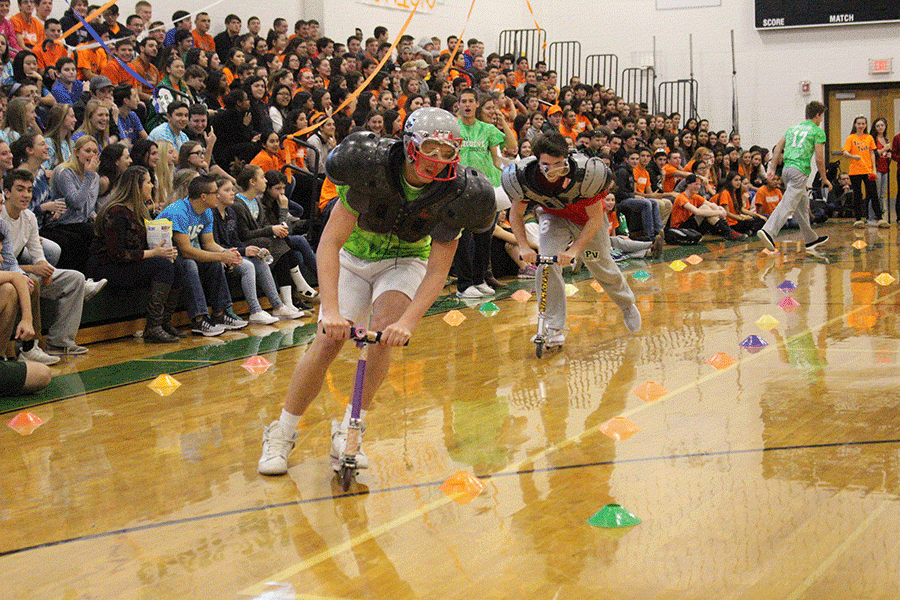 Students race their way around the gym on scooters while being shot at with yarn balls.