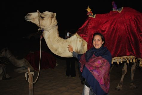 Angie DeLima standing with a camel in Dubai.