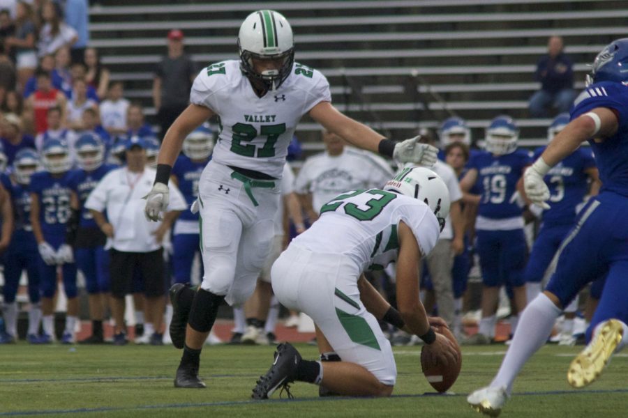 Jake Ciocca (27) tries an extra point for Pascack Valley off the hold of Mike Garay (23).  