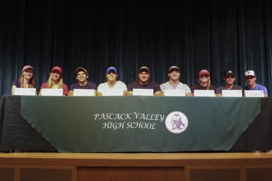 Nine seniors sit at the podium after deciding which college to commit to. Arianna Quevedo was unable to attend the event.