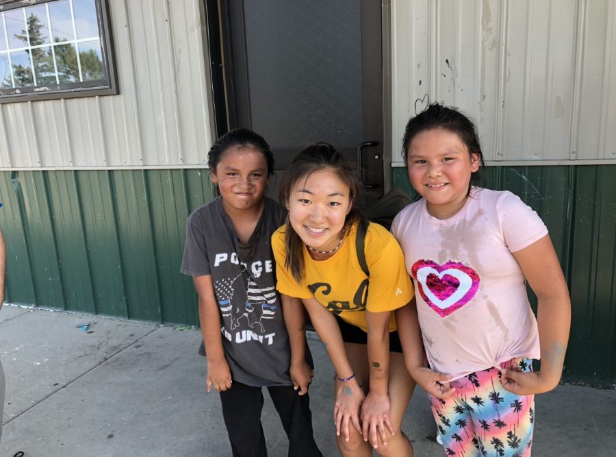 Junior Ellie Kim stands with two children outside of the Cheyenne River Youth Project building. She addresses the importance to give back to communities in need following the service trip to South Dakota.